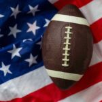 An American football resting on a background of the American flag
