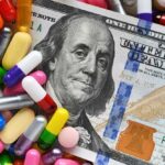 A hundred dollar bill surrounded by various colorful capsules and pills