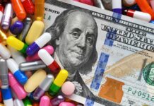 A hundred dollar bill surrounded by various colorful capsules and pills