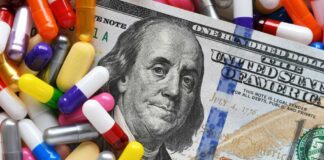 A hundred dollar bill surrounded by various colorful capsules and pills