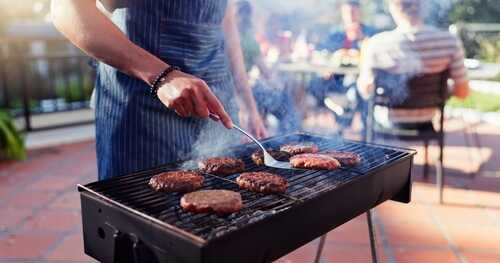 shutterstock_2475095419.jpg Person grilling burgers at an outdoor barbecue