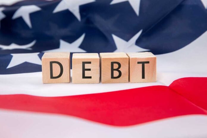shutterstock_2620543149.jpg Wooden blocks spelling 'DEBT' on an American flag background