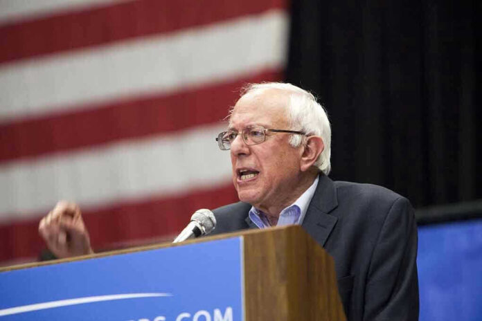 Man speaking at podium, American flag background.