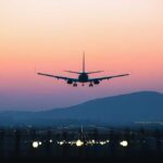 An airplane approaching for landing against a colorful sunset sky
