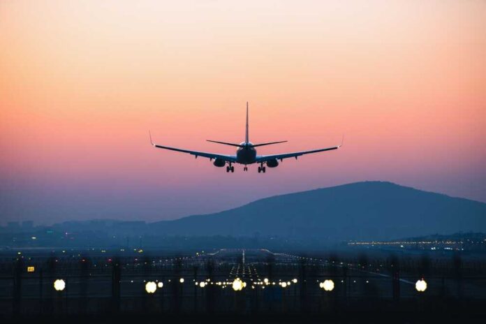 shutterstock_2323496231.jpg An airplane approaching for landing against a colorful sunset sky