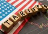 Wooden blocks spelling 'TARIFFS' on a background of the US flag and financial charts