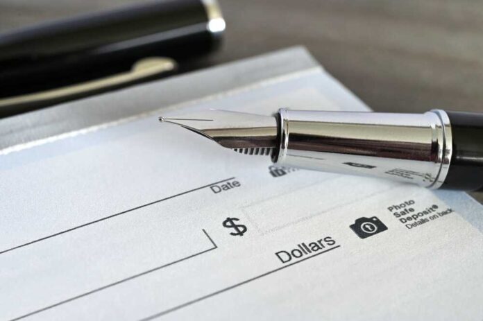 Close-up of a fountain pen poised over a blank check