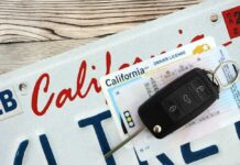 California license plate, driver's license, and car keys on a wooden surface