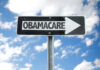 Directional sign pointing towards Obamacare against a blue sky