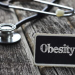 A stethoscope next to a sign that reads 'Obesity'