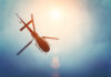 A helicopter flying against a bright sky