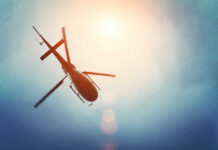 A helicopter flying against a bright sky
