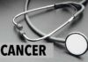 A stethoscope on a dark surface with the word 'CANCER' prominently displayed
