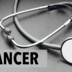 A stethoscope on a dark surface with the word 'CANCER' prominently displayed