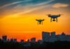 Two drones flying during colorful sunset skyline