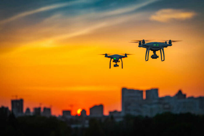 Two drones flying during colorful sunset skyline