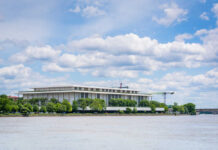 A modern building by the river under a cloudy sky