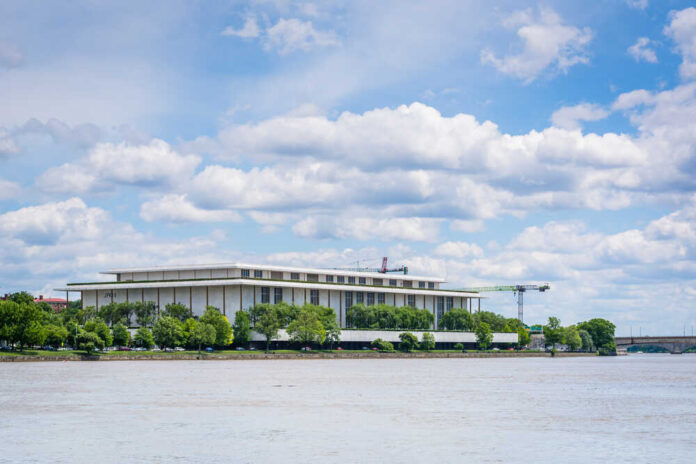 A modern building by the river under a cloudy sky