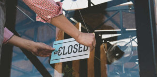 Person flipping closed sign on glass door
