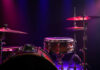 Close-up of a drum set with colorful stage lighting