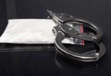 Handcuffs placed next to a bag of white powder