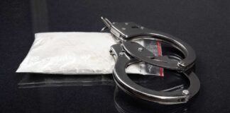 Handcuffs placed next to a bag of white powder