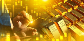 Hand writing near stacked gold bars and charts