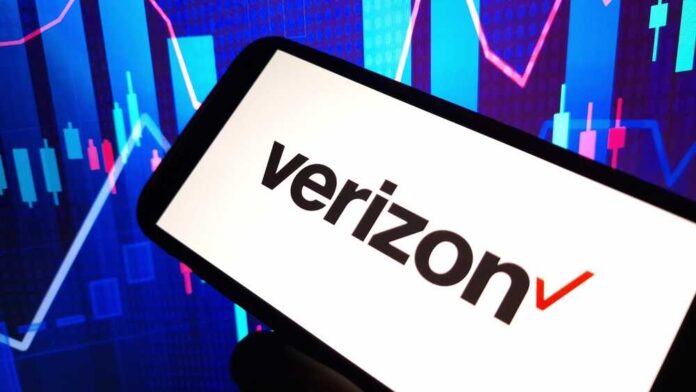 A smartphone displaying the Verizon logo in front of a colorful stock market graph