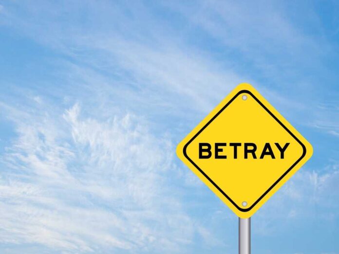 A yellow warning sign with the word 'BETRAY' against a blue sky