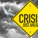 Economic Chaos Topples Restaurant Giant Yellow sign reading Crisis Just Ahead with stormy sky