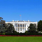 The White House with flags and trees.