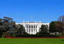 The White House with flags and trees.