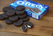 A pile of Oreo cookies next to an open package on a wooden surface