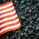 US flag on pile of dark coal rocks