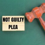 A wooden gavel next to a sign that reads 'NOT GUILTY PLEA'