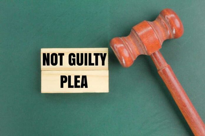 A wooden gavel next to a sign that reads 'NOT GUILTY PLEA'