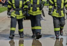 Three firefighters walking in uniform on a wet surface