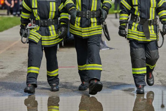 Three firefighters walking in uniform on a wet surface