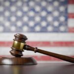 Trump’s Wannabe Assassin Sentenced A wooden gavel resting on a sound block with an American flag background