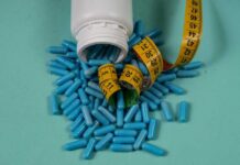 Spilled blue capsules and a measuring tape on a turquoise background