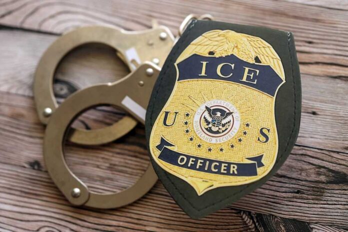 shutterstock_2704937373.jpg ICE officer badge next to handcuffs on a wooden surface