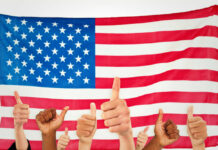 Thumbs up in front of American flag.