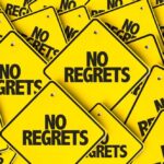 A collection of yellow signs displaying the phrase 'No Regrets'