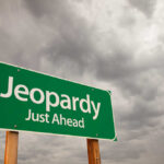 Retail Giant’s Last Stand — 175 Stores in Jeopardy Green road sign indicating 'Jeopardy' ahead with a cloudy sky