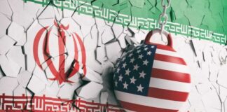 A wrecking ball painted with the American flag is breaking through a wall featuring the Iranian flag