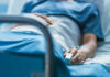 A patient lying in a hospital bed with a monitoring device in hand