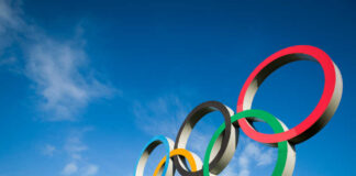 Five colorful Olympic rings against a clear blue sky