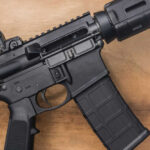 Black rifle on wooden surface close up