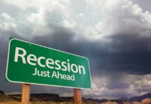 Wall Street Bear Bets Trump Recession A green road sign indicating 'Recession Just Ahead' against a cloudy sky