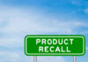 Green sign with product recall text and sky background